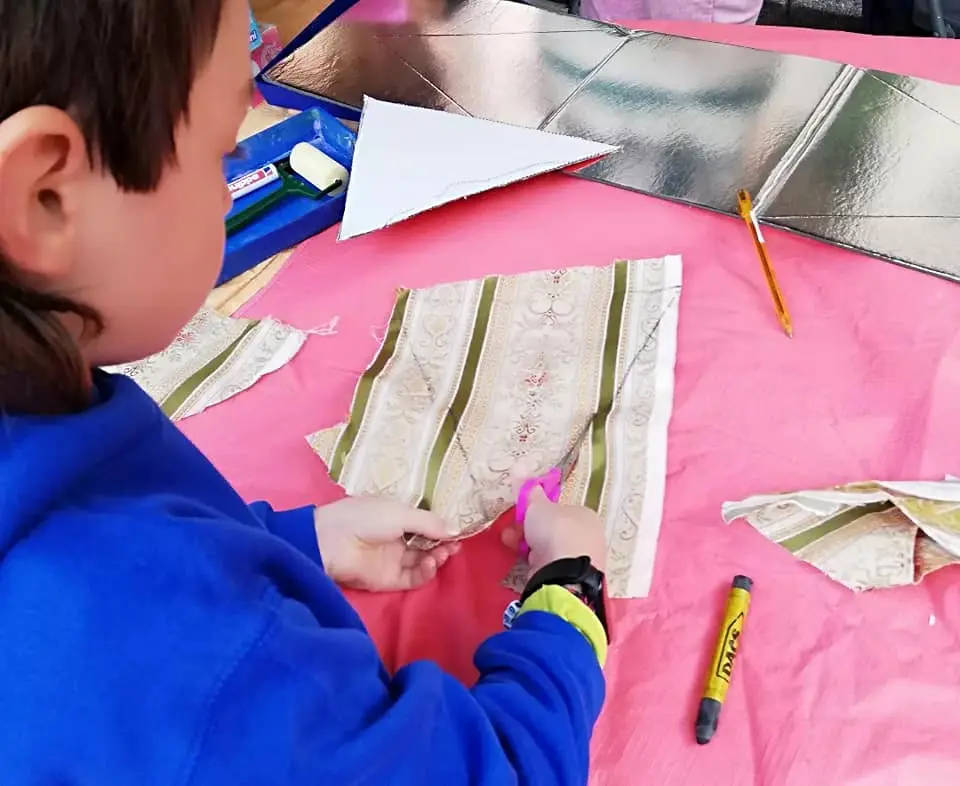 Un nen retallant roba en el marc del taller de banderoles amb roba de segona mà | © Escola Bressol El Petit Montgrí - Facebook