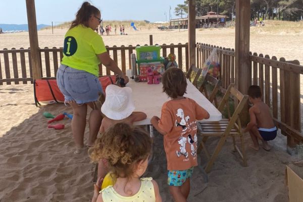 Una monitora i diversos nens i nenes jugant al Mini Beach Club de l'Estartit