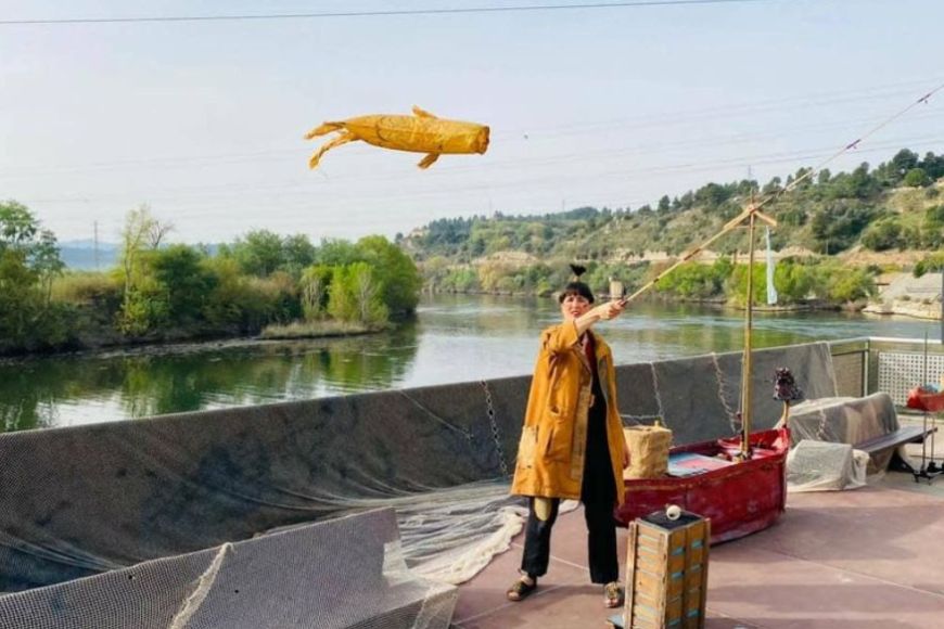 Una actriu fent volar un cometa amb la forma d'un peix Una actriu fent volar un cometa amb la forma d'un peix